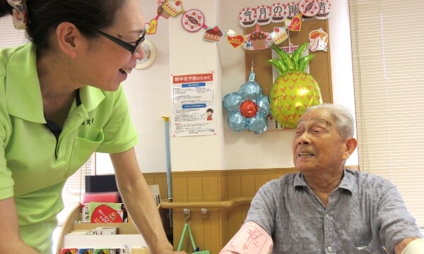 スタッフがご利用者へ健康チェックを行なっている写真