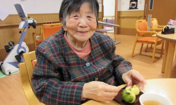 笑顔で微笑む、和菓子を食べるご利用者の写真