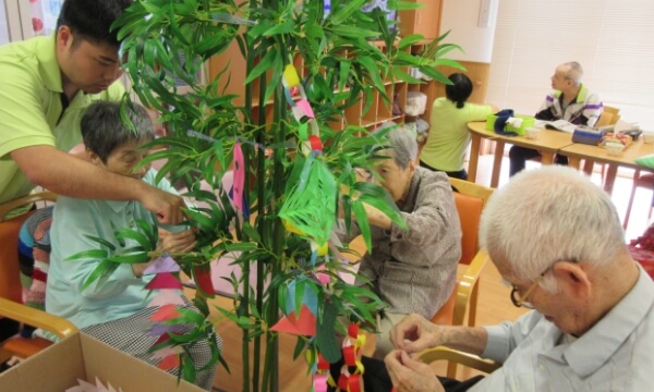 笹の葉に七夕飾りをつけるご利用者の写真