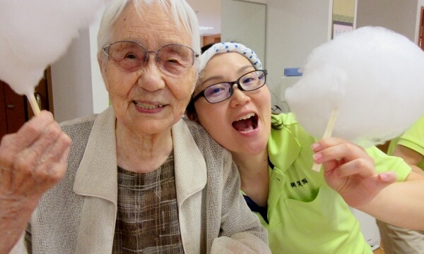綿菓子を手に持ち、夏祭りを楽しむご利用者とスタッフの写真