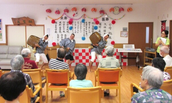 敬老会でスタッフの出し物を見るご利用者の写真