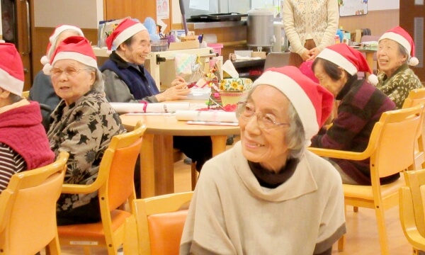 サンタ帽子をかぶり、笑顔で楽しむご利用者の写真